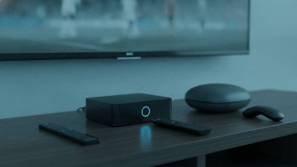 A streaming stick, a set-top box and a round streaming box with their remotes on a TV console